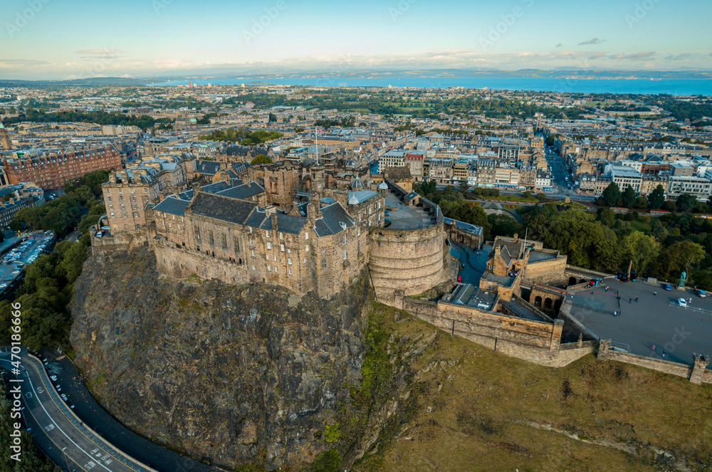 Top aerial view of Edinburgh in Scotland, with the castle dominates the skyline, casting its shadow over the surrounding historic town occupying commanding position on volcanic crag with cliffs