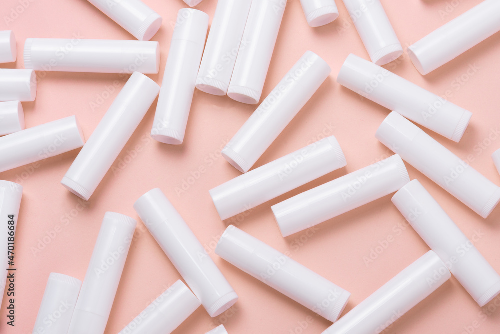 Lot of white plastic lip gloss tubes on pink background - obrazy, fototapety, plakaty 