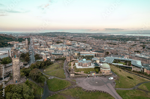Aerial sunrise view of Calton Hill in Edinburgh, Scotland surrounded by old buildings. Locals use the hill to observe the vastness of the city, enjoy festivals, or attend to spiritual activities