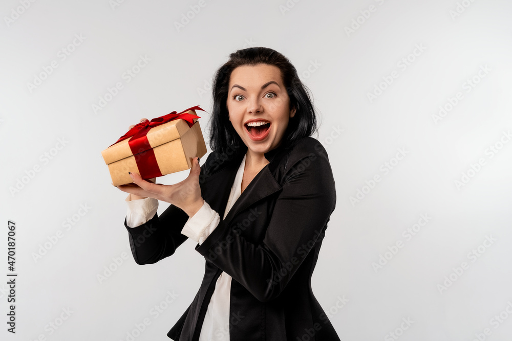 Portrait of a happy businesswoman opening gift box and looking at camera, standing over white background. Holidays, celebration and lifestyle concept Portrait of a happy businesswoman opening gift box and looking at camera, standing over white background. Holidays, celebration and lifestyle concept