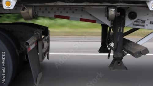 Driving beside tractor trailer. Detail of truck wheels, trailer and trailer hitch or fifth wheel.