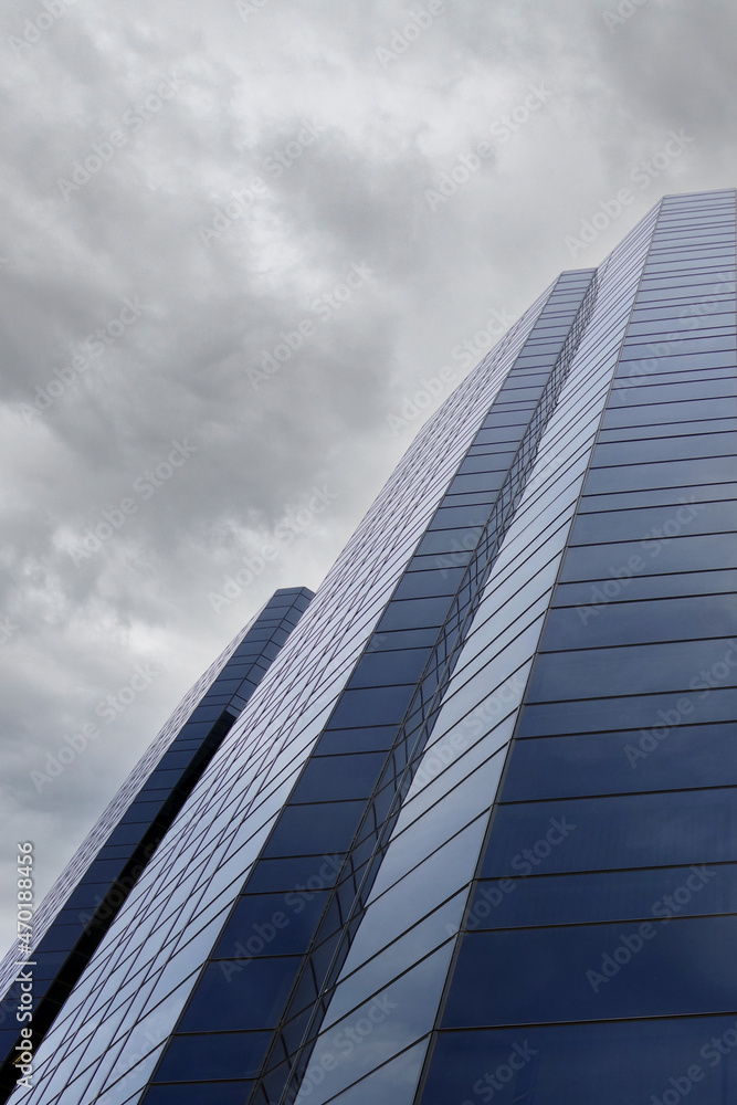 Low angle partial view of a skyscraper facade under cloudy sky Low angle partial view of a skyscraper facade under cloudy sky