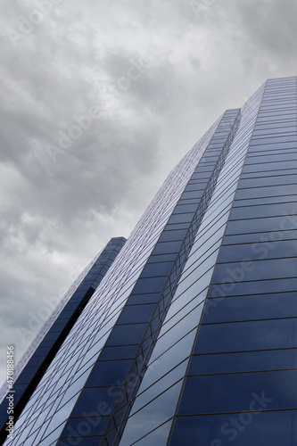 Low angle partial view of a skyscraper facade under cloudy sky