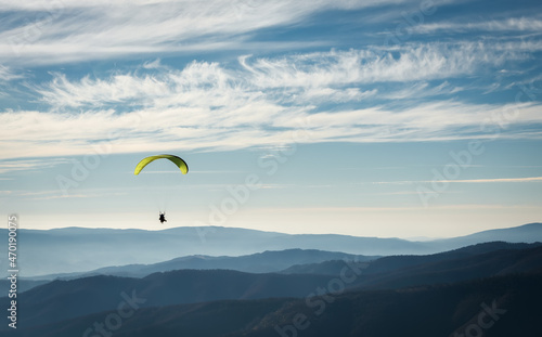 A paraglider soars in the sky over the foggy Carpathian valley. Paragliding. Concepts: adventure, determination, extreme sports. Alpine ski resort. Rest in Ukraine, Carpathian.