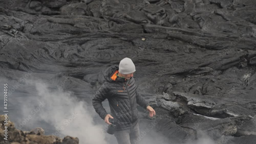 Photographer Holding Camera Amongst Smoking Lava Field Photographer Holding Camera Amongst Smoking Lava Field