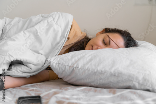 Young woman goes to sleep Phone addiction, insomnia. try to fall asleep. Sleep tracking on the phone. Circadian rhythm.