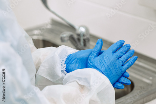 doctor in a medical uniform and blue gloves washes his hands. Close up.