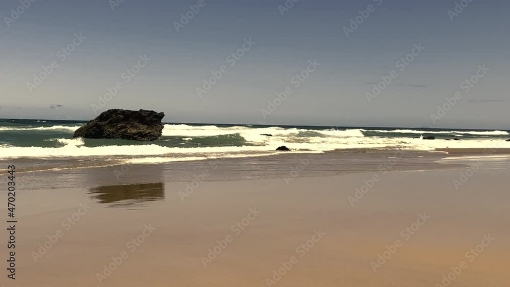 Landscape of the impact of wave action on a huge boulder located in the surf zone of a sandy beach in a coastal, Australia. Landscape of the impact of wave action on a huge boulder located in the surf zone of a sandy beach in a coastal, Australia.