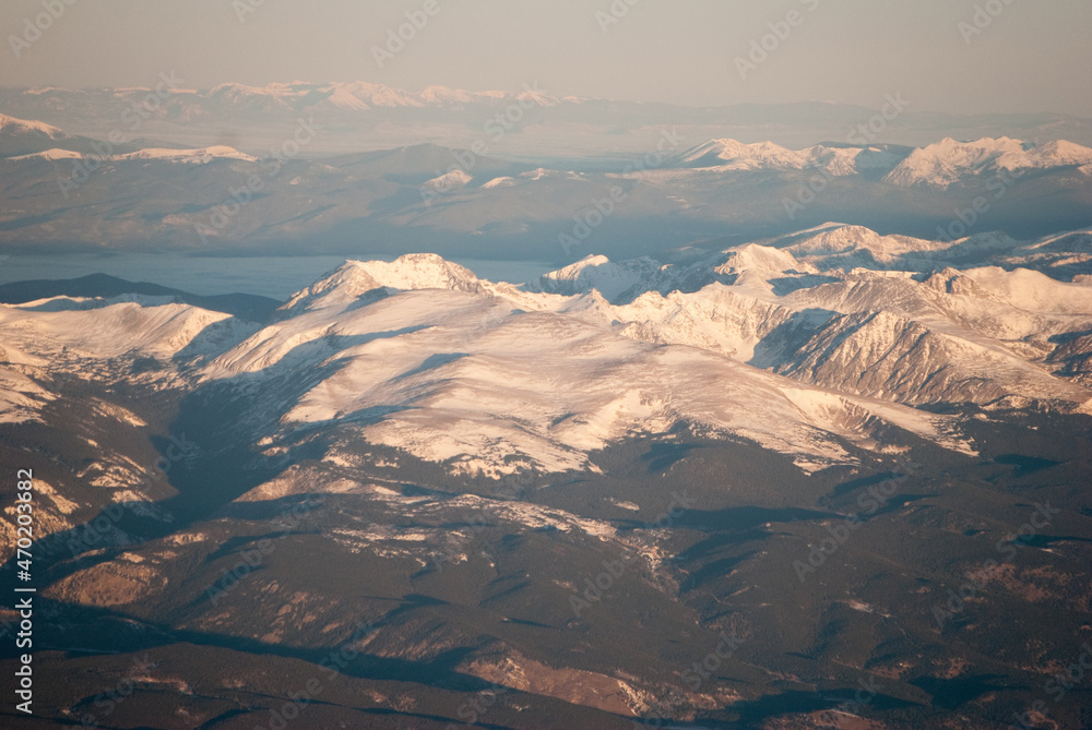 Obraz premium Snowy Rocky Mountains peaks at Sunrise from an airplane