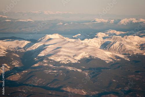 Snowy Rocky Mountains peaks at Sunrise from an airplane © alma