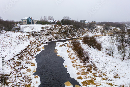 Winter aerial view of the river with snow-covered banks. Beautiful rural landscape. Cottages on the high bank of the river. Cold weather. Tosna river, Ulyanovka village, Leningrad region, Russia. photo