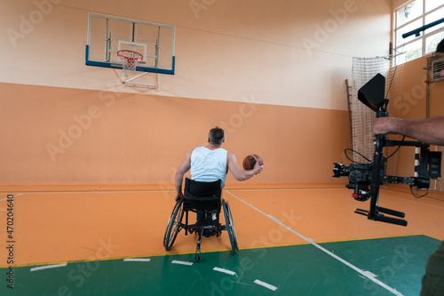 a cameraman with professional equipment records a match of the national team in a wheelchair playing a match in the arena photo