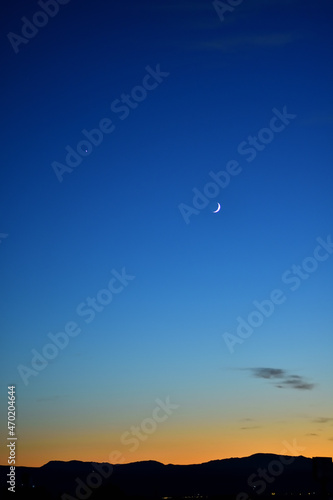The moon and Venus in the sunset sky over the silhouette of the mountains