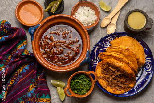 Birria tacos and broth on a gray background. Mexican food photo
