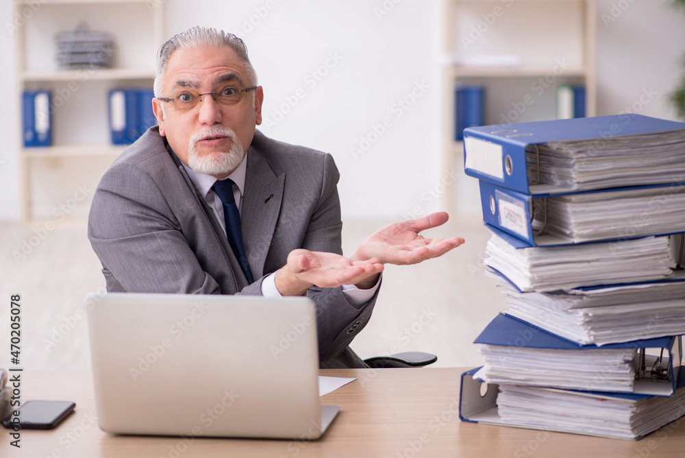 Old male employee unhappy with excessive work in the office Old male employee unhappy with excessive work in the office
