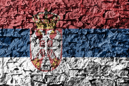 Serbia flag depicted on a stone wall. The texture of the stone blends perfectly with the colors of the banner