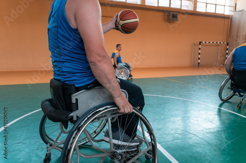 Disabled War veterans mixed race and age basketball teams in wheelchairs playing a training match in a sports gym hall. Handicapped people rehabilitation and inclusion concept