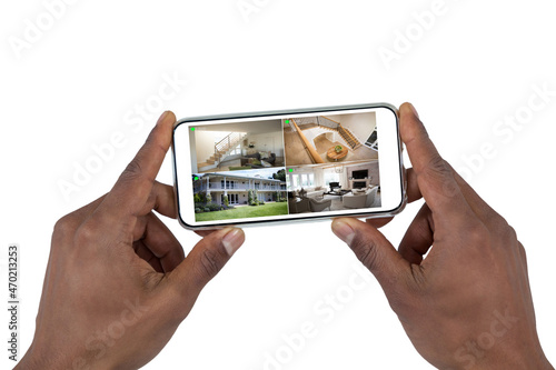 Hands of african american man holding smartphone with view of home from security cameras on screen