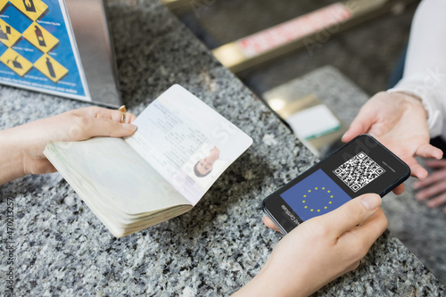 Woman at airport holding documents and smartphone with covid 19 vaccine passport