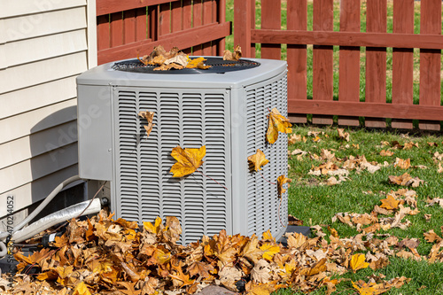 Dirty air conditioning unit cover in leaves during autumn. Home air conditioning, hvac, repair, service, fall cleaning and maintenance. photo
