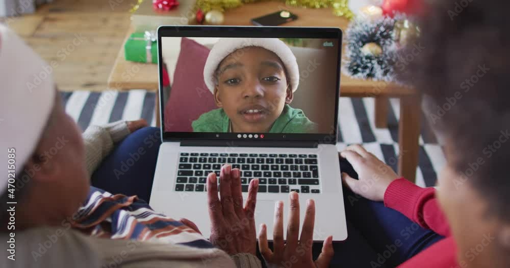 African american mother and daughter using laptop for christmas video call with boy on screen African american mother and daughter using laptop for christmas video call with boy on screen