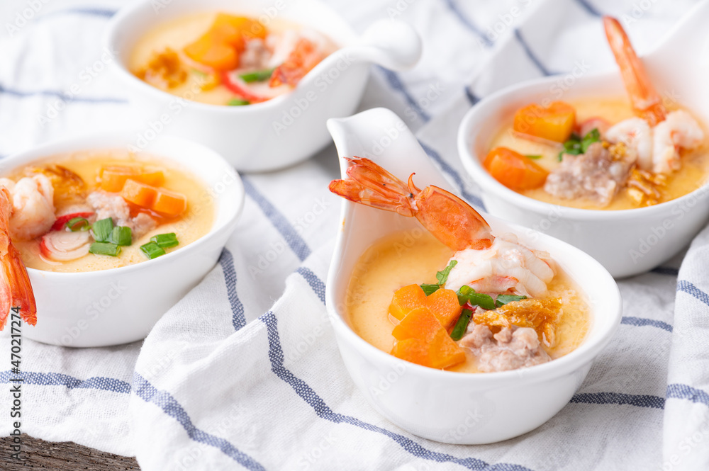 Homemade style steamed egg with shrimp and vegetables in a ceramic bowl on wooden table. healthy food concept. Homemade style steamed egg with shrimp and vegetables in a ceramic bowl on wooden table. healthy food concept.