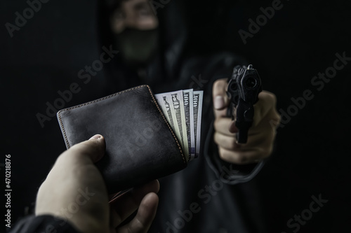 Billede på lærred Man's hand holds out purse of money to robber with gun