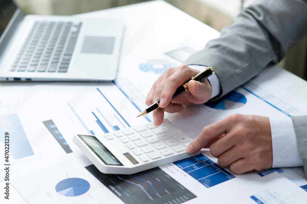 Businessman working with finance calculate on calculator and using computer laptop and document data chart in office room. Businessman working with finance calculate on calculator and using computer laptop and document data chart in office room.