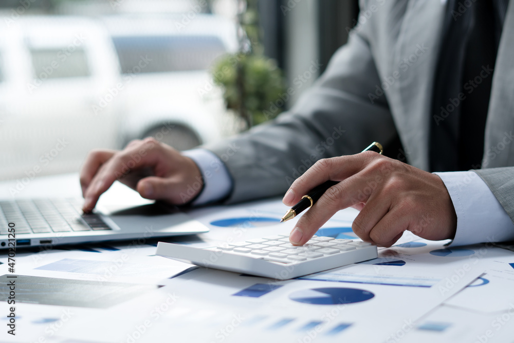 Businessman pen pointing graph chart in this month and use calculator for Plans to improve quality next month. Businessman pen pointing graph chart in this month and use calculator for Plans to improve quality next month.