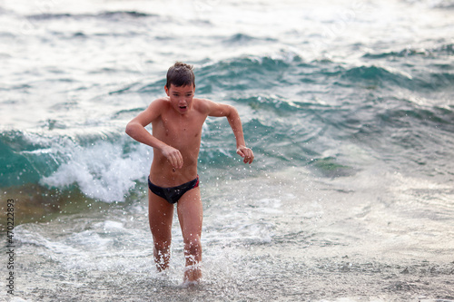 Boy bathes in cold water in the sea in winter, hardening