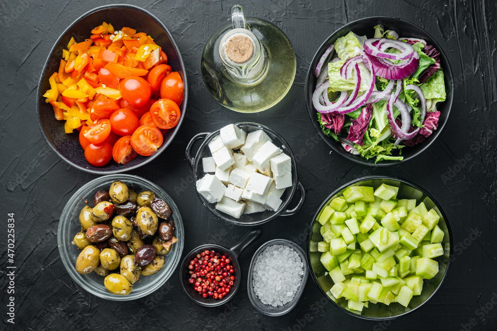 Greek salad main ingredients: fresh olives mix, feta cheese, tomatoes, pepper, on black background, top view flat lay