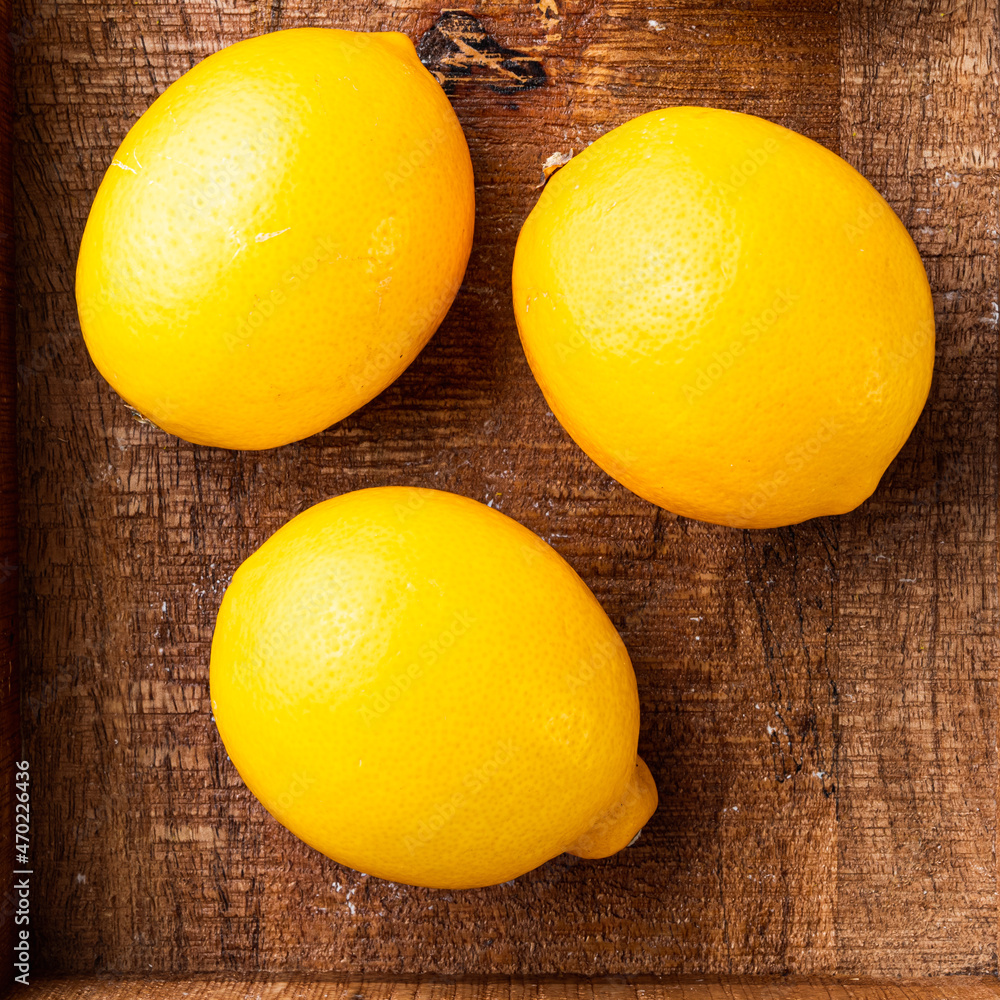 Fresh lemons, in wooden box, on gray background, top view flat lay