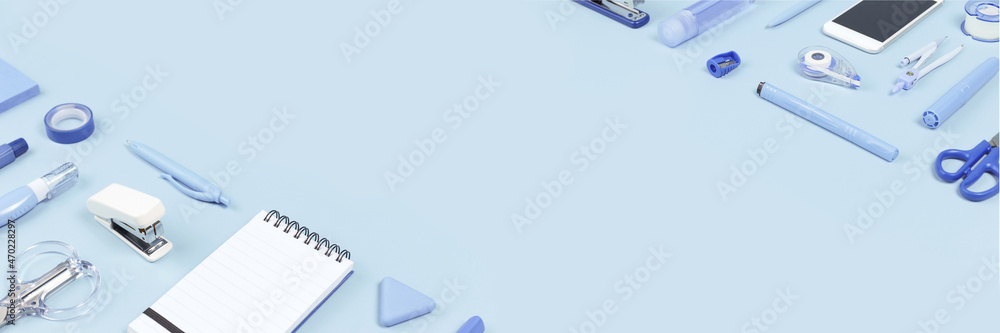 Assorted office and school white and blue stationery and smartphone on background as corner border. copy space for back to school or education craft office work concept. Blue monochrome long banner Assorted office and school white and blue stationery and smartphone on background as corner border. copy space for back to school or education craft office work concept. Blue monochrome long banner