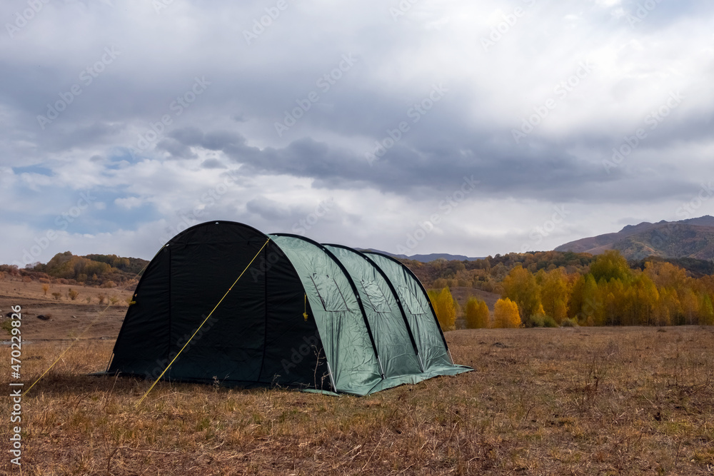 Green large basecamp tent on colorful mountains background.