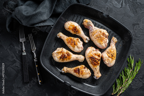 Grilled Chicken leg drumstick with herbs, poultry meat. Black background. Top view