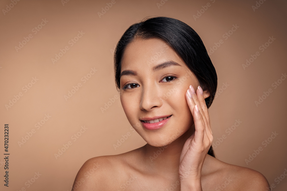Beautiful asian woman applying organic cosmetics to face skin smiling to camera
