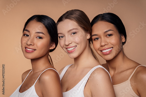 Portrait of there multi-ethnic beautiful young women hugging, smiling to camera
