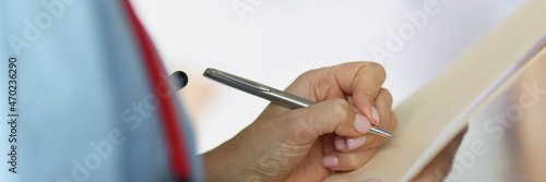 Doctor filling out patient medical documents with ballpoint pen in ward closeup