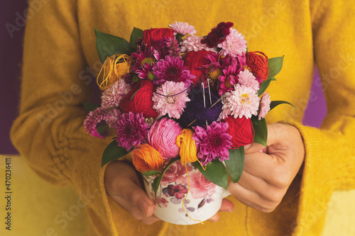 Decoration in a a cup of embroidery thread, needles and multicolored flowers