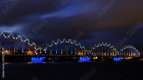 Reflection of night lights at dawn on the Daugava in Riga against the background of the railway bridge © IHAR