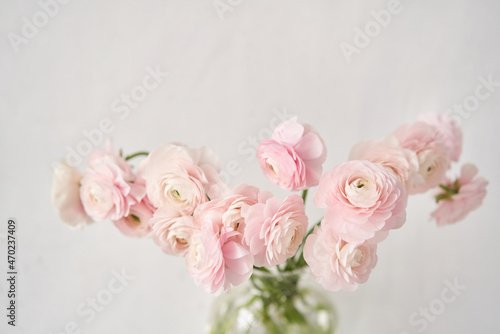 The background of ranunculus colors is gently pink. A riotous peony-shaped rose bouquet