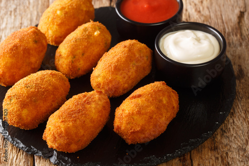 Canvastavla Spanish croquettes with salted cod served with sauces close-up on a slate plate on the table