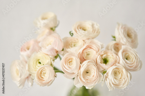 The background of ranunculus colors is gently pink. A riotous peony-shaped rose bouquet