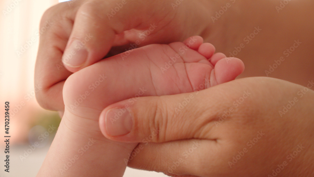Mother doing massage for her healthy infant baby. Small caucasian newborn laying on his belly while his mother is performing a massage for his small feet and developing toes. . Mother doing massage for her healthy infant baby. Small caucasian newborn laying on his belly while his mother is performing a massage for his small feet and developing toes. .