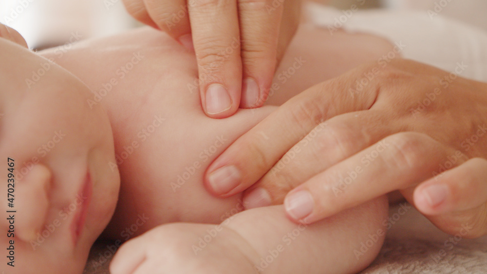 Mother doing massage on her healthy sleeping infant baby. Small caucasian newborn resting and laying on his belly while his mother is performing a massage for his small back and developing muscles. . Mother doing massage on her healthy sleeping infant baby. Small caucasian newborn resting and laying on his belly while his mother is performing a massage for his small back and developing muscles. .