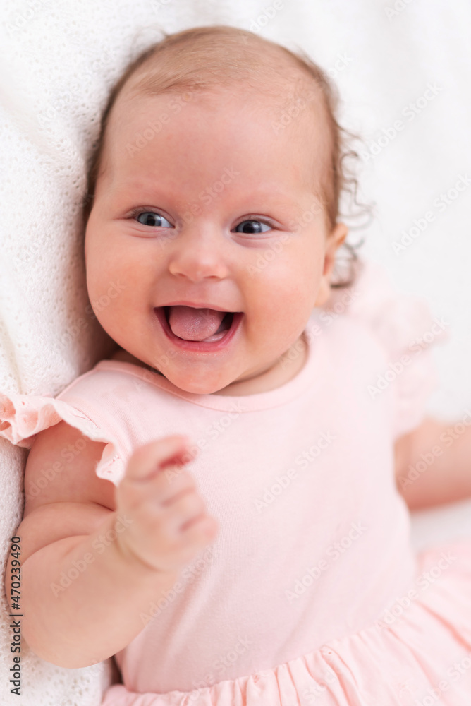 Cute happy baby lies on a white sheet and is covered with a woolen cloth Cute happy baby lies on a white sheet and is covered with a woolen cloth