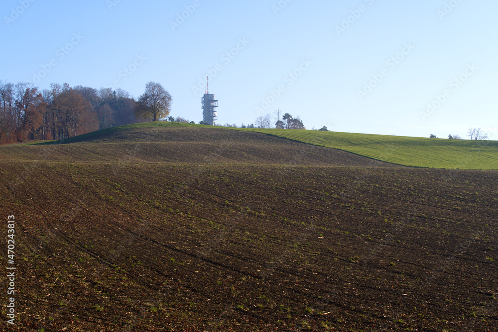 Scenic panoramic landscape with freshly harvested field  and communications tower in the background on a sunny autumn day. Photo taken November 12th, 2021, Zurich, Switzerland.