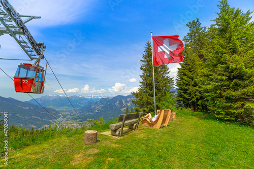 Woman in Brambruesch in Switzerland. Swiss cable car of Chur city with Swiss flag. Chur skyline in Grisons canton. Red cable car cabin from Chur to Kanzeli and Brambruesch. photo