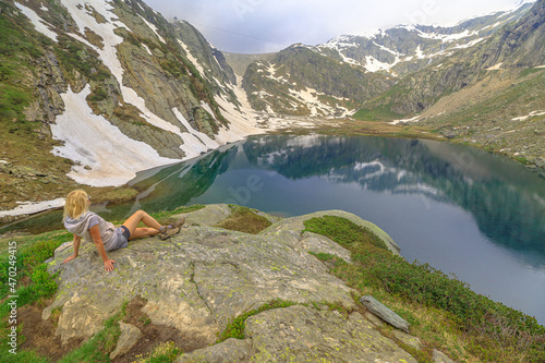 Tourist woman trekking with poles by lakefront of White Lake. Swiss reservoir in Maggia Valley of Ticino canton with Cavagnoo dan. Top of tramway station from San Carlo town of Switzerland. photo