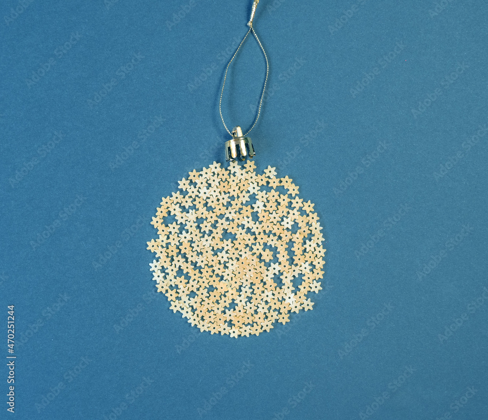 Christmas decoration on a tree in the form of a ball of pasta on a blue paper background, top view. Conceptual photo.